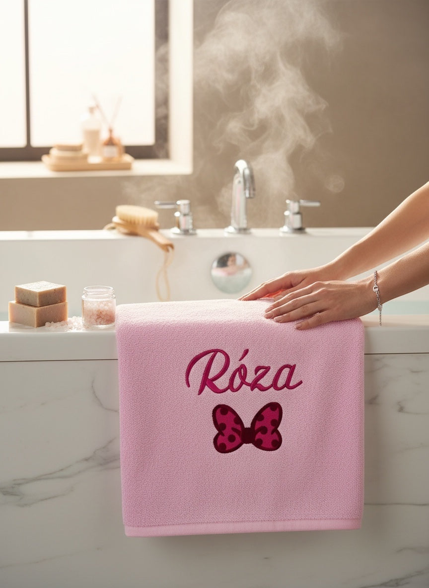 csinosan pink 100% cotton bath towel with custom embroidered name and polka dot bow design in a bathroom setting